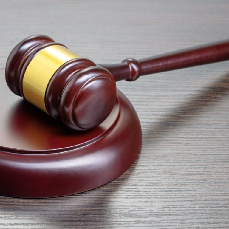 single judge's wooden gavel on wooden table